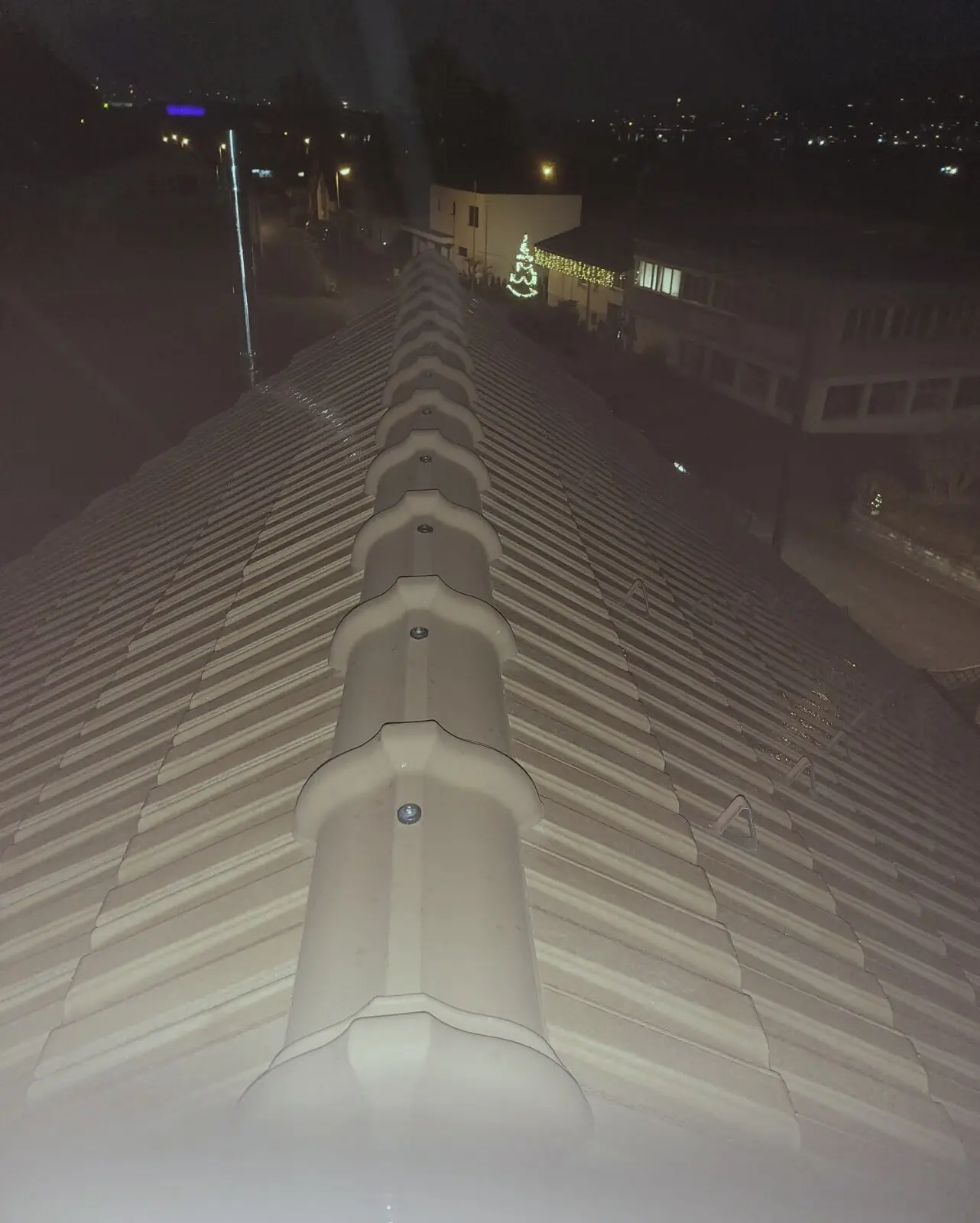 Firstziegel eines Steildachs bei Abenddämmerung