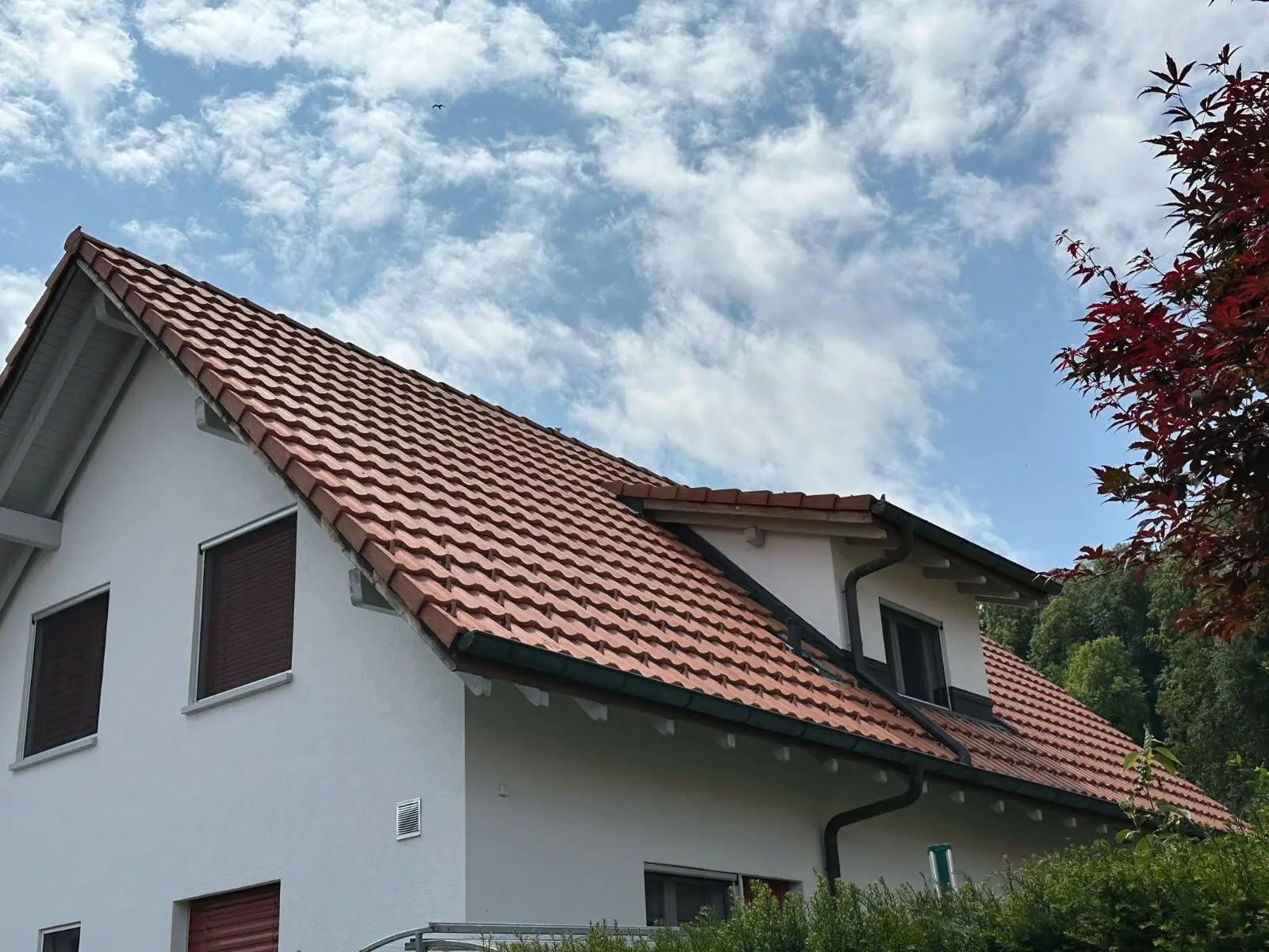 Neue Dachrinne und Ablaufrohr an einem fertig eingedeckten Ziegeldach